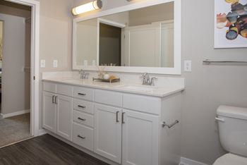 White bathroom vanity with dual sinks, large mirror, and designer fixtures.